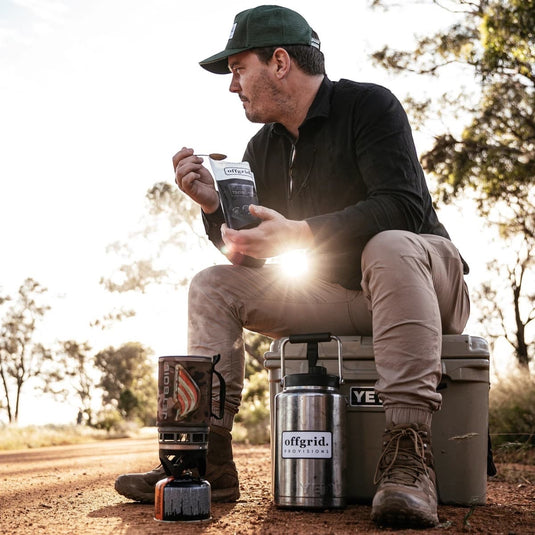 Cadetshop hiker eating an Offgrid Provisions cherry acai breakfast bowl from a pouch while sitting on a cooler outdoors